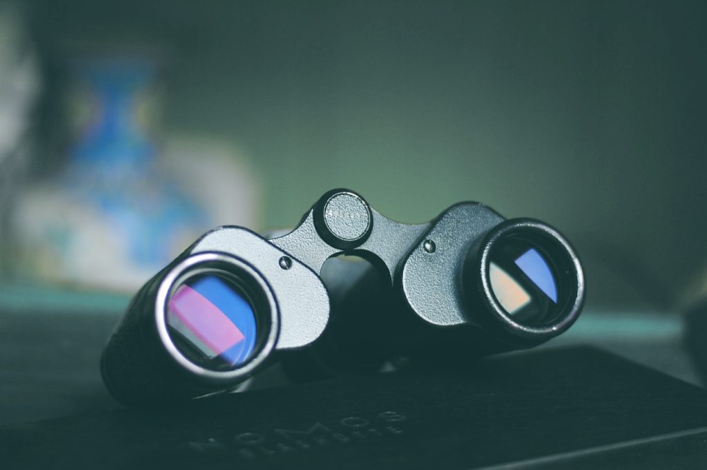 Primo piano di un binocolo posizionato su una superficie, con riflessi colorati visibili nelle lenti, a dimostrazione del modo in cui gli sforzi SEO strategici possono migliorare la visibilità del tuo sito su Google.