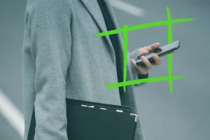 Persona in cappotto grigio che tiene in mano uno smartphone e una cartella nera, con sovrapposizione grafica verde, che simboleggia l'innovazione e il successo dell'e-mail marketing.