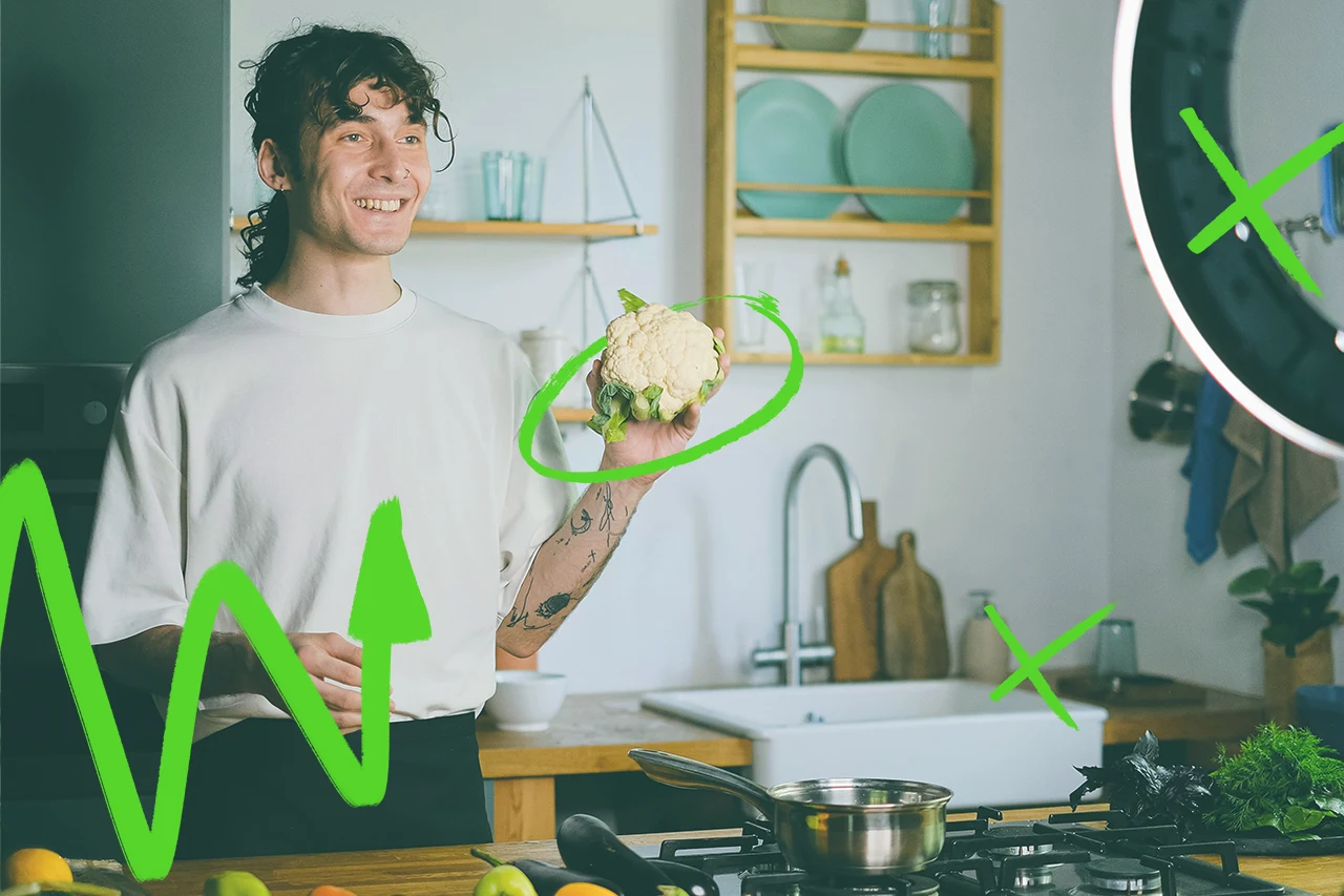 Una food influencer italiana sorridente tiene in mano un cavolfiore in una cucina.