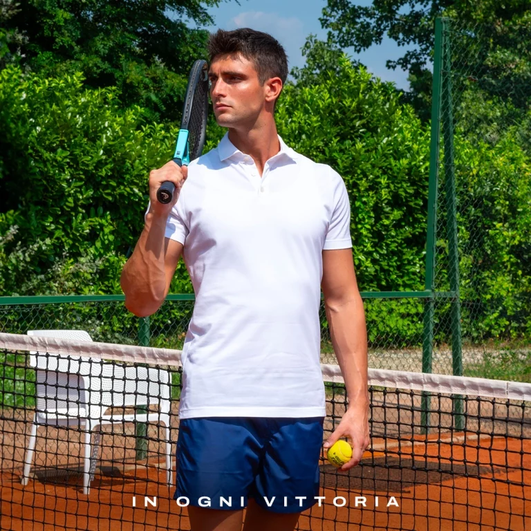 Modello con polo bianca e pantaloncini Julipet su un campo da tennis, con il testo "In ogni vittoria"